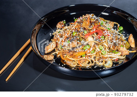 Udon noodles with meat, mushrooms and vegetables. Sprinkled with sesame seeds. Asian food, roast on black background, 93279732