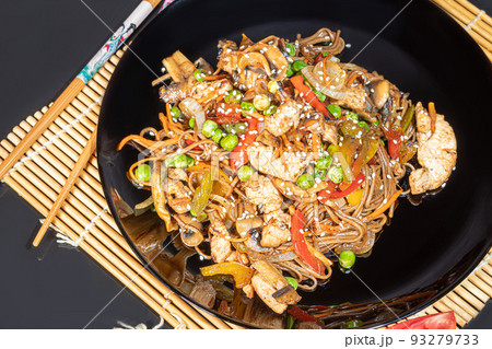 Udon noodles with meat, mushrooms and vegetables. Sprinkled with sesame seeds. Asian food, roast on black background, 93279733