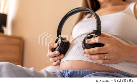 Pregnancy therapy music. Pregnant woman listening to music. Mother belly listen headphones sound. Pregnancy, medicine health care and people concept. 93280295