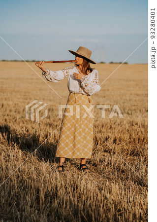 Woman playing on woodwind wooden flute - ukrainian telenka or tylynka in wheat field. Folk music 93280401