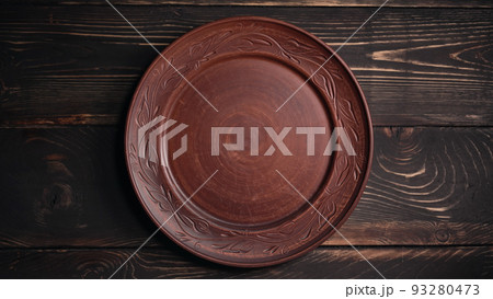 Empty ukrainian clay plate from wooden table. Top view. National tableware with handmade ornament Empty ukrainian clay plate from wooden table. Top view. National tableware with handmade ornament 93280473