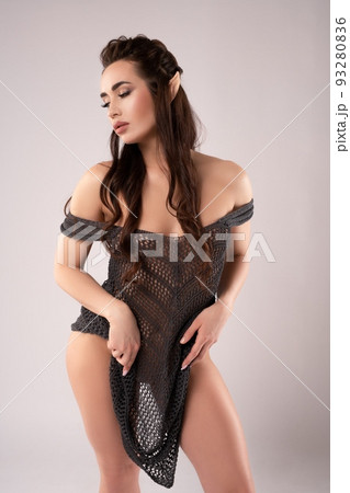 Confident young woman with bare shoulders looking at camera in gray studio 93280836