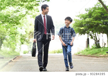 笑顔で話しながら歩くと男子小学生と父親 93284395