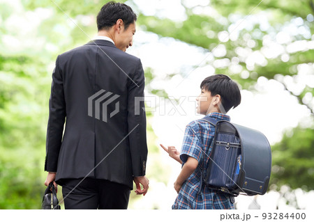 話しながら歩くと男子小学生と父親の後姿 93284400