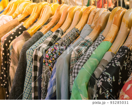 Bright colored clothes on wooden hangers on the market, Clothes shop in the outdoor market, Clothing trade. 93285031