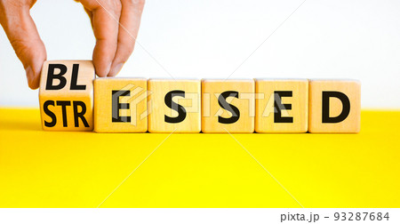 Blessed or stressed symbol. Businessman turns wooden cubes and changes the concept word Stressed to Blessed. Beautiful yellow table white background. Business blessed or stressed concept. Copy space. 93287684