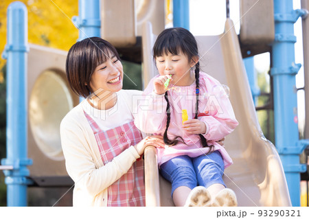 公園でシャボン玉で遊ぶ女の子と保育士 公園でシャボン玉で遊ぶ女の子と保育士 93290321