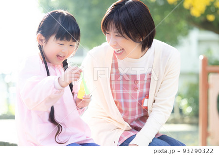 公園でシャボン玉で遊ぶ女の子と保育士 93290322