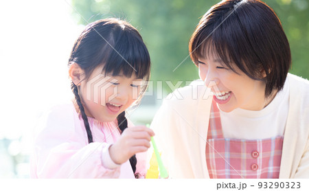 公園でシャボン玉で遊ぶ女の子と保育士 93290323