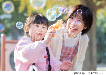 公園でシャボン玉で遊ぶ女の子と保育士 93290325