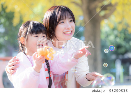 公園でシャボン玉で遊ぶ女の子と保育士 93290358