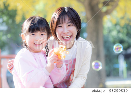 公園でシャボン玉で遊ぶ女の子と保育士 93290359