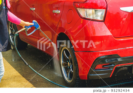 Car wash service., Self-cleaning car wash., The young man was washing the car to be clean and safe from germs., The young man is spraying water., Wash cars and wash wheels for cleanliness. 93292434
