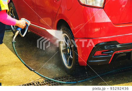 Car wash service., Self-cleaning car wash., The young man was washing the car to be clean and safe from germs., The young man is spraying water, wash cars and wash wheels for cleanliness. 93292436