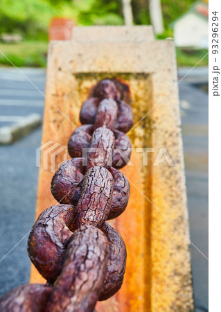 Old rusted chain link connecting dividers by water 93296294