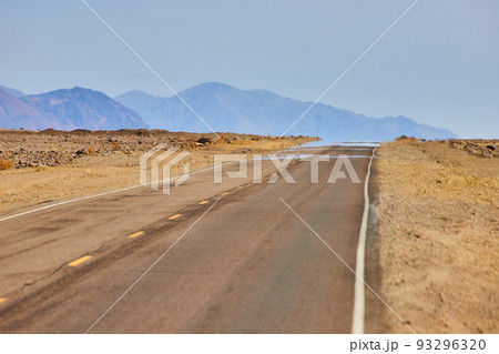 Mirage on road in desert landscape with mountains 93296320