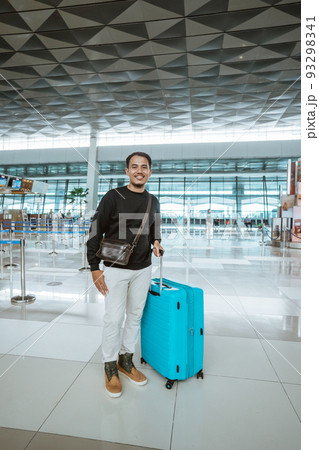man carrying a luggage in airport terminal man carrying a luggage in airport terminal 93298341