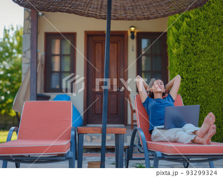 Young business woman working at computer by hotel pool. 93299324