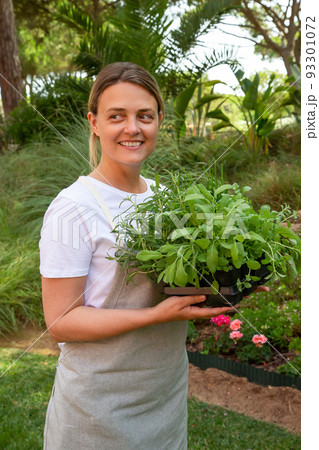 Happy woman holding salad seedlings Happy woman holding salad seedlings 93301072