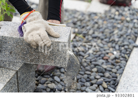 墓参り　お墓の花瓶の水を捨てるシニア女性  墓掃除 93302801