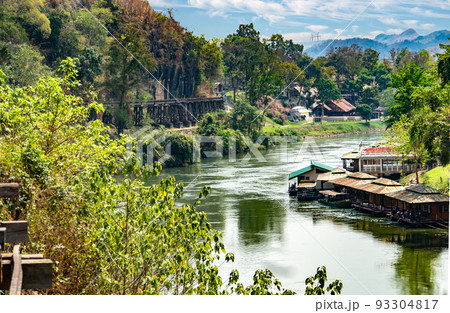 The River Kwai in Thailand with houseboats. Along the cliff is a bridge built during the war by prisoners. 93304817