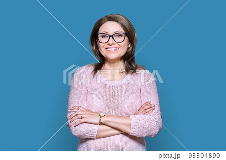 Attractive Middle aged woman looking at camera on blue background 93304890