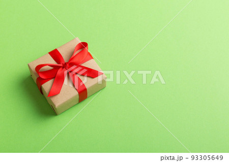 Wrapped christmas or other holiday handmade present in craft paper with colored ribbon. Present box, decoration of gift on table, top view with copy space Wrapped christmas or other holiday handmade present in craft paper with colored ribbon. Present box, decoration of gift on table, top view with copy space 93305649