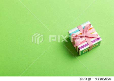 wrapped Christmas or other holiday handmade gift box in color paper with ribbon on colored background. Present box, decoration of gift on colored table, top view with copy space wrapped Christmas or other holiday handmade gift box in color paper with ribbon on colored background. Present box, decoration of gift on colored table, top view with copy space 93305650