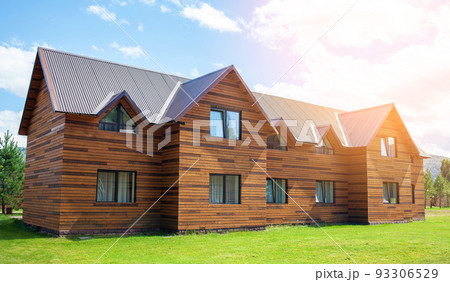 Two-storey wooden cottage with windows nature with a green lawn. Sale or purchase of new houses. A hotel for tourists. 93306529
