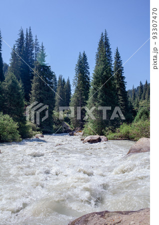 A beautiful stormy mountain river of milky hue flows rapidly among large stones and boulders near the mountains and the blue sky. The mountain river fascinates and attracts attention. A beautiful stormy mountain river of milky hue flows rapidly among large stones and boulders near the mountains and the blue sky. The mountain river fascinates and attracts attention. 93307470