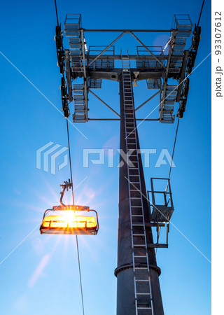 Empty ski-lift chair and cable car mast Empty ski-lift chair and cable car mast 93307612