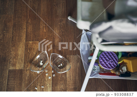 A baby on a high chair, dropped a cup of noodle soup on the wooden floor. The concept of accidents in the kitchen is dangerous for small children in the house. High quality photo 93308837
