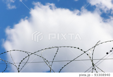 barbed wire as a restriction . Against the backdrop of a bright blue sky  93308940