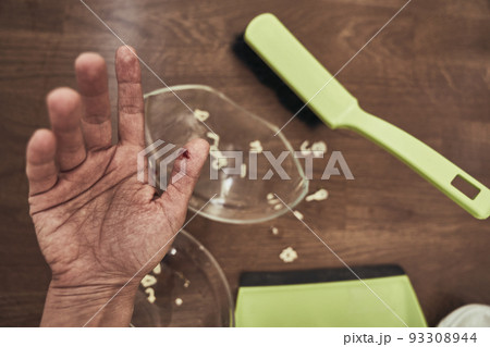 Selective focus on a cut female finger on the background of a split cup and a brush with a dustpan for cleaning. A wound with blood received when cleaning broken dishes. High quality photo 93308944