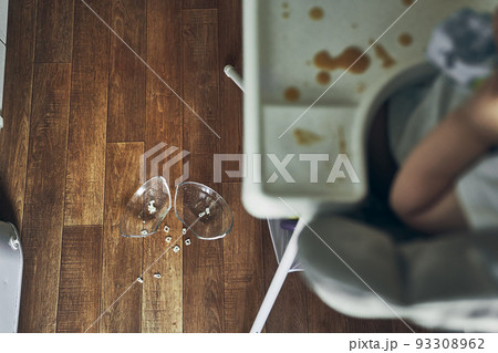 A baby on a high chair, dropped a cup of noodle soup on the wooden floor. The concept of accidents in the kitchen is dangerous for small children in the house. High quality photo 93308962
