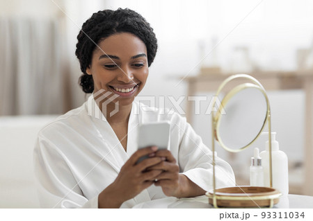 Black Woman With Smartphone Reading Beauty Hacks While Getting Ready At Home 93311034