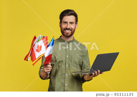 Learn foreign languages. Happy man holding laptop and international flags, middle aged male teacher with computer Learn foreign languages. Happy man holding laptop and international flags, middle aged male teacher with computer 93311135