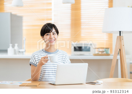 リビングでテレワーク中に休憩する女性 リビングでテレワーク中に休憩する女性 93312314