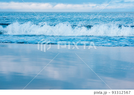 seascape, ocean surf on a smooth sandy beach, the sky is reflected in the wet sand 93312567