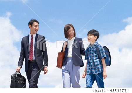 青空のもと笑顔を見せながら歩く3人家族 93312754