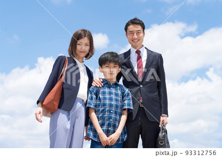 青空のもとカメラに視線を向ける3人家族 93312756