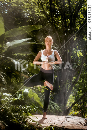 Portrait of young woman practicing yoga in tropic environment 93313154