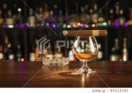 close up view of cigar and glass of cognac on color back.  close up view of cigar and glass of cognac on color back.  93313161