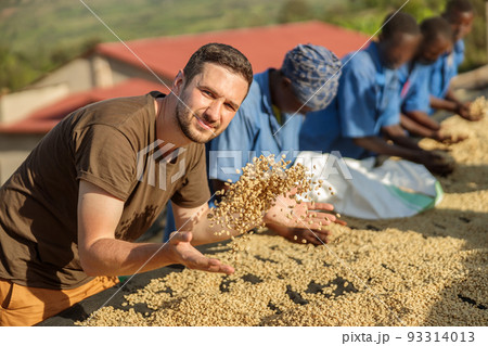 Young man tossing coffee beans with his hands Young man tossing coffee beans with his hands 93314013