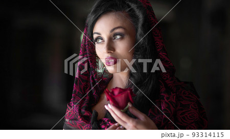 Close-up portrait of a young woman with a red rose. 93314115