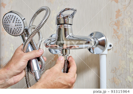 Plumber tightening fixing nut on flexible hose of shower head. 93315964
