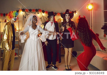 Group of happy adult friends in spooky costumes meeting at Halloween fancy dress party 93316049