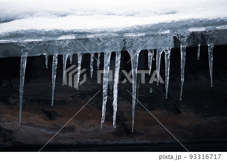 Icicles on roof. Dangerous icing. Ice stalactites on house. Poor maintenance of residential buildings in winter. Icicles on roof. Dangerous icing. Ice stalactites on house. Poor maintenance of residential buildings in winter. 93316717