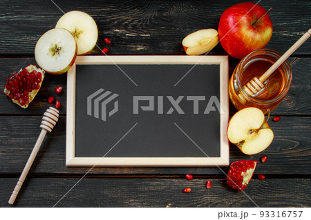 Rosh Hashanah celebration. Honey, apples and pomegranates on dark wooden background. Frame for congratulatory text. Jewish traditional religious holiday. Rosh Hashanah celebration. Honey, apples and pomegranates on dark wooden background. Frame for congratulatory text. Jewish traditional religious holiday. 93316757