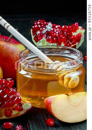 Traditional Jewish religious holiday Rosh Hashanah. Apples, pomegranates and honey on dark wooden background. Vertical photo. Traditional Jewish religious holiday Rosh Hashanah. Apples, pomegranates and honey on dark wooden background. Vertical photo. 93316758